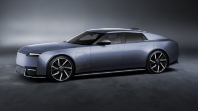Side profile of the new Jaguar Type 01 electric luxury grand tourer in metallic blue-gray, featuring a long hood, sleek four-door design and large alloy wheels.